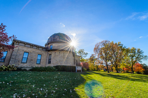 Washburn Observatory on a grassy green hill in front of a sunny, blue sky.
