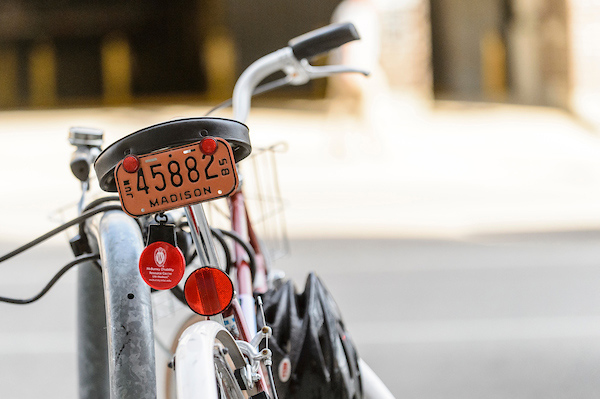 A bicycle with rear reflectors parked at a bike rack on campus.