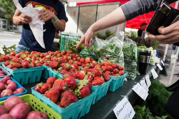 A shopper points to a pint of strawberries for purchase at the Farmers Market.
