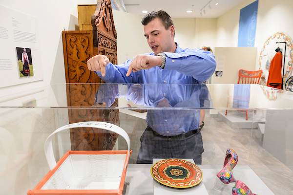 A man wearing a blue collared shirt points to an exhibit in a museum.