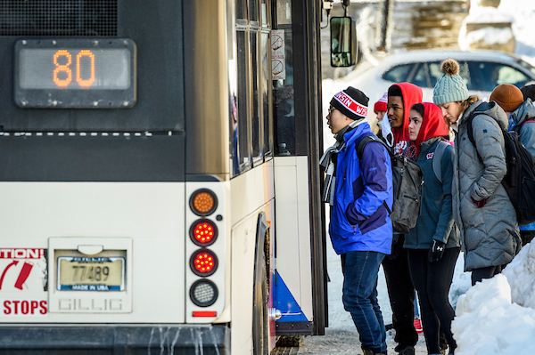 A line of students waits to board the bus.