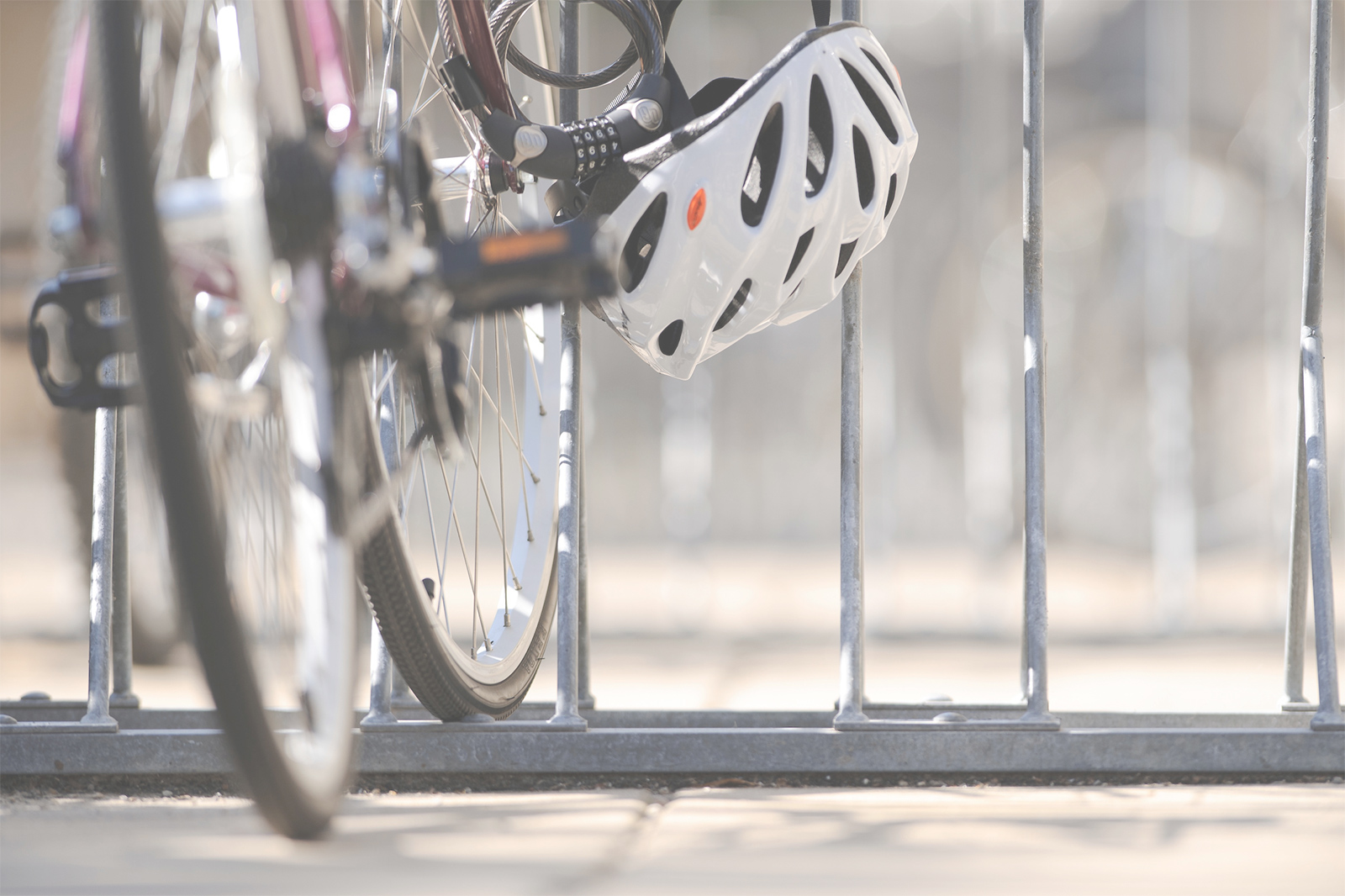 A helmet hangs off a bike parked at a bike rack on campus.