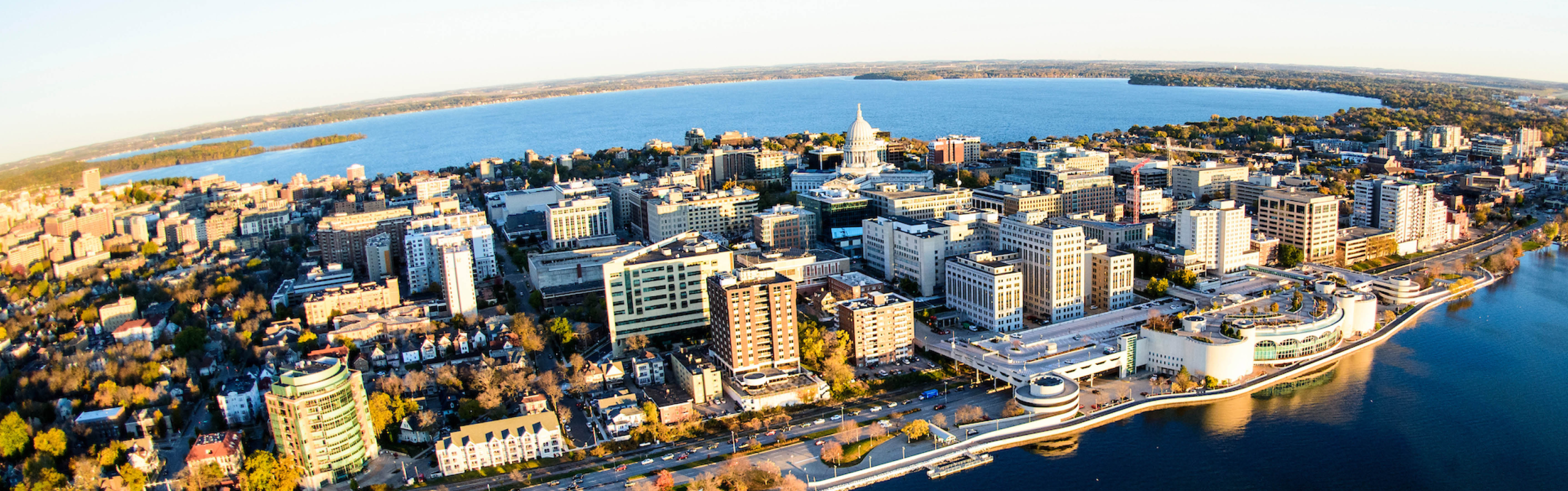 The skyline of downtown Madison with glassy blue lakes on either side.