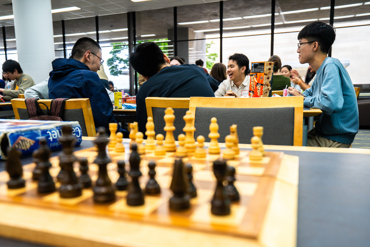 A group of students play a card game around a table.